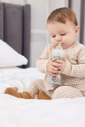 Photo of Cute little baby with money in bottle on bed at home