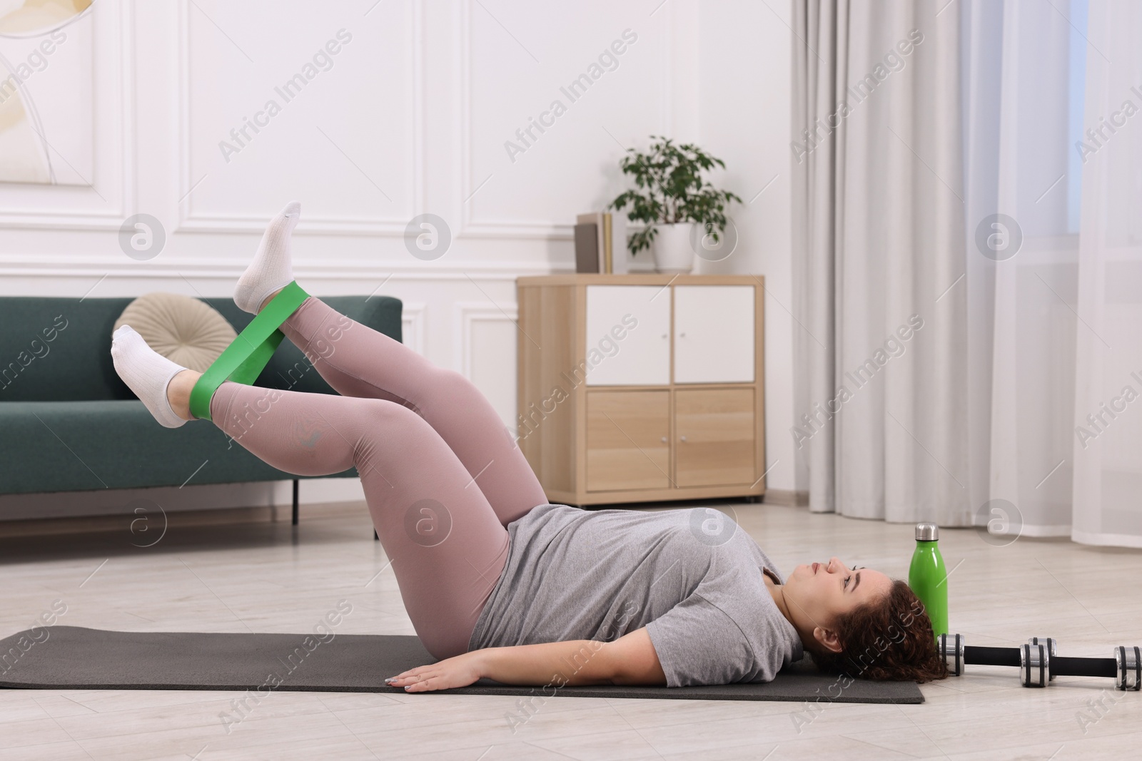 Photo of Woman training with resistance band at home