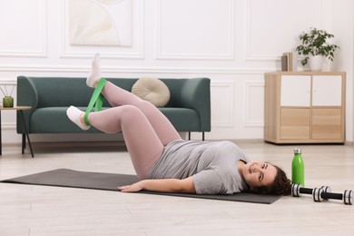 Photo of Woman training with resistance band at home