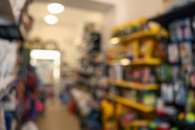 Photo of Blurred view of shelves with different products in pet shop