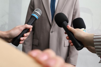 Photo of Group of journalists interviewing businessman indoors, closeup