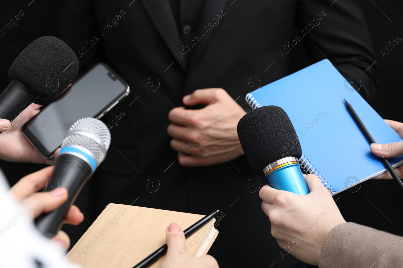 Photo of Group of journalists interviewing businessman on black background, closeup