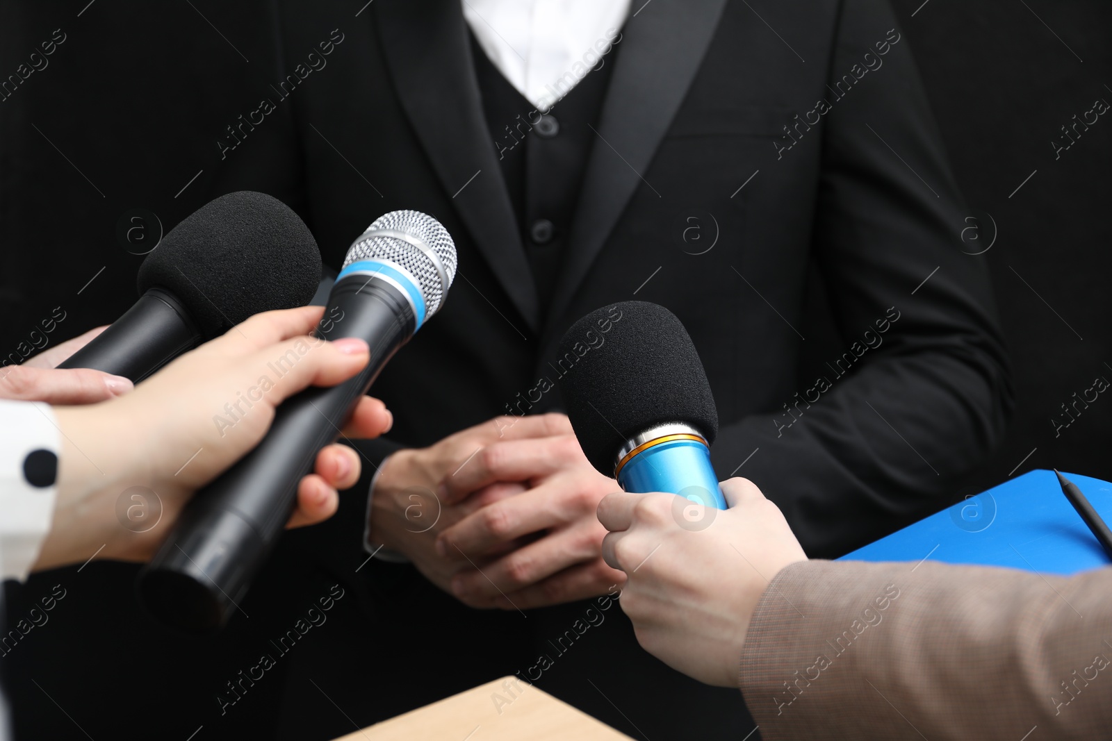 Photo of Group of journalists interviewing businessman on black background, closeup