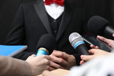 Photo of Group of journalists interviewing businessman on black background, closeup