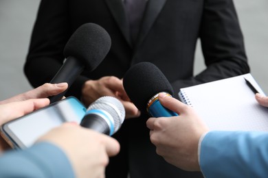 Photo of Group of journalists interviewing businesswoman on grey background, closeup