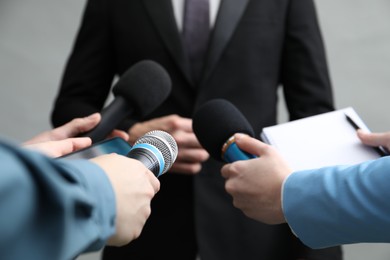 Photo of Group of journalists interviewing businesswoman on grey background, closeup