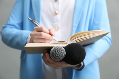 Photo of Journalist with microphones taking notes on grey background, closeup