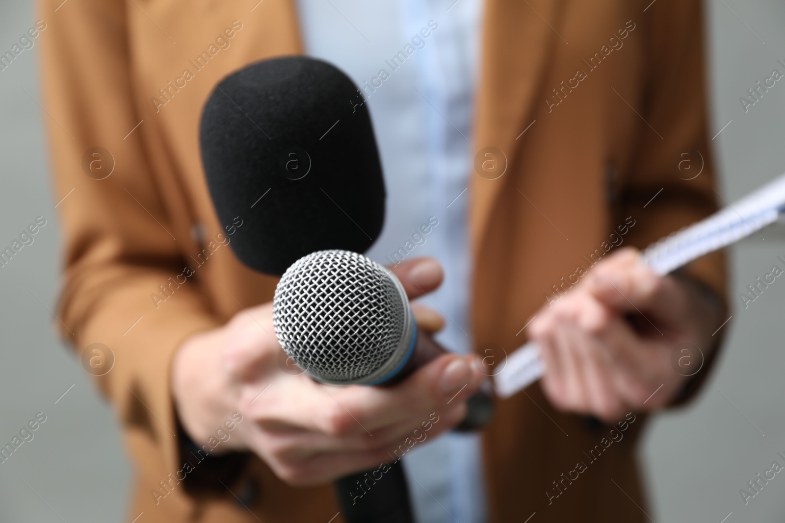 Photo of Journalist with microphones and notebook on grey background, closeup