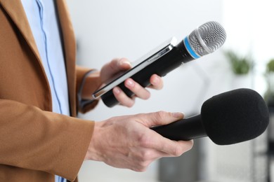 Photo of Journalist with microphones and smartphone indoors, closeup