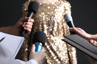 Photo of Group of journalists interviewing celebrity on black background, closeup