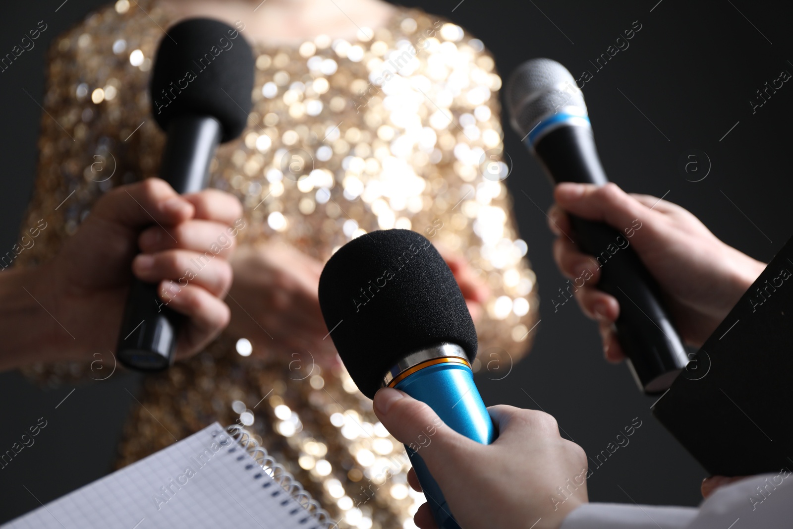 Photo of Group of journalists interviewing celebrity on black background, closeup