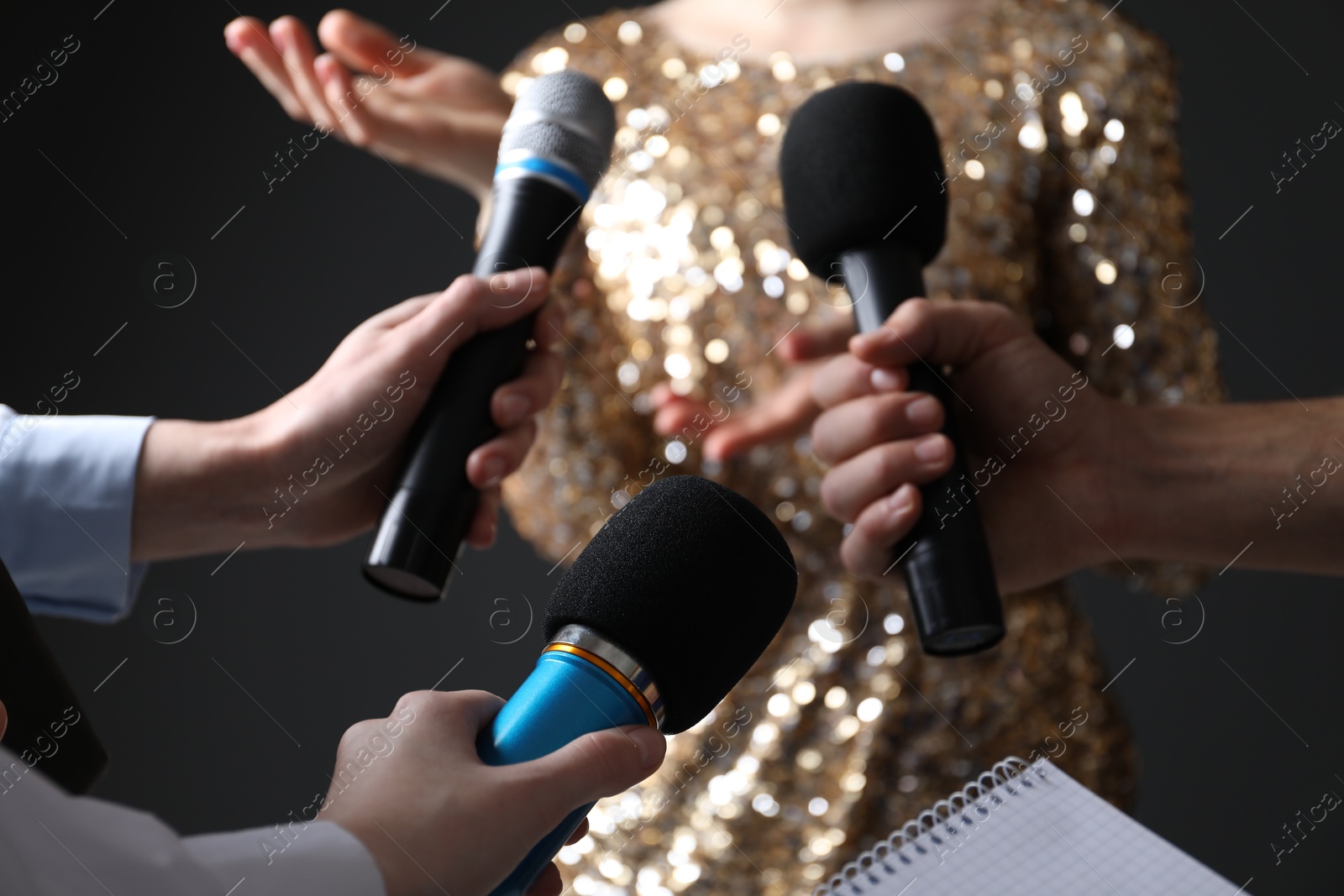 Photo of Group of journalists interviewing celebrity on black background, closeup