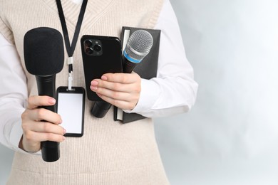 Photo of Journalist with microphones, smartphone and notebook on grey background, closeup. Space for text