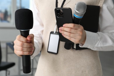 Photo of Journalist with microphones, smartphone and notebook indoors, closeup