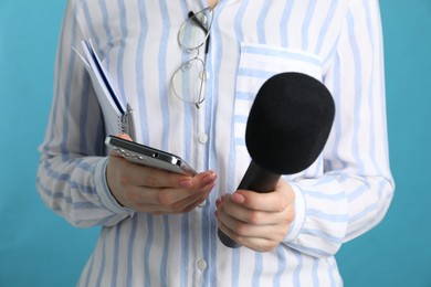 Photo of Journalist with microphone and smartphone on light blue background, closeup