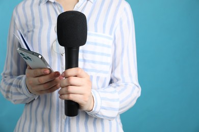 Photo of Journalist with microphone and smartphone on light blue background, closeup. Space for text