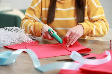 Photo of Woman with hot glue gun making craft at table indoors, closeup