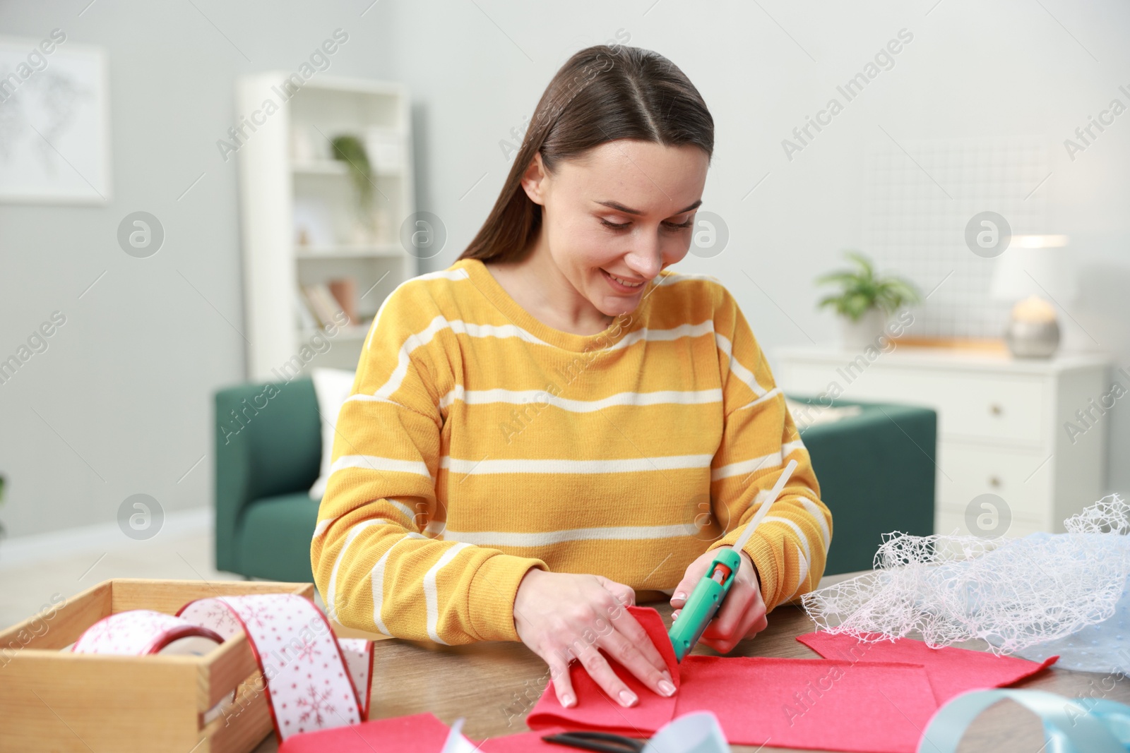 Photo of Woman with hot glue gun making craft at table indoors