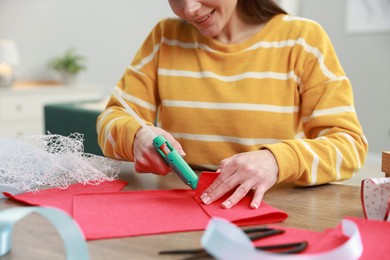 Photo of Woman with hot glue gun making craft at table indoors, closeup