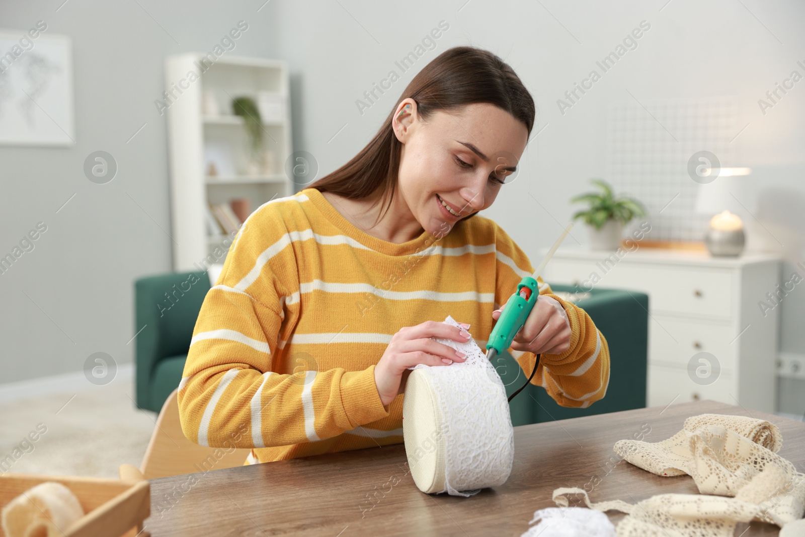 Photo of Woman with hot glue gun making craft at table indoors