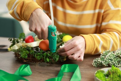 Photo of Woman with hot glue gun making craft at table indoors, closeup