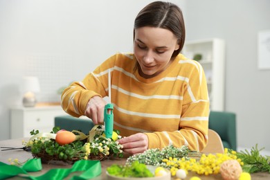 Photo of Woman with hot glue gun making craft at table indoors