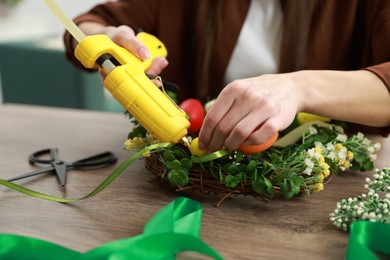 Woman with hot glue gun making craft at table indoors, closeup