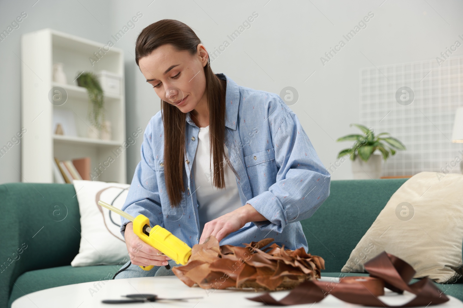 Photo of Woman with hot glue gun making craft at table indoors