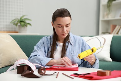 Photo of Woman with hot glue gun making craft at table indoors