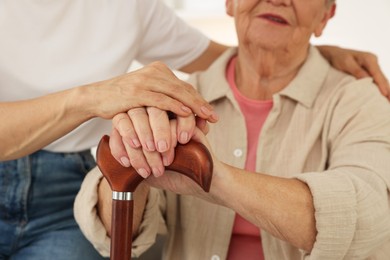 Photo of Caregiver supporting senior woman at home, closeup