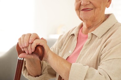 Photo of Senior woman with walking cane indoors, closeup