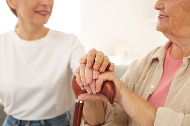 Photo of Caregiver supporting senior woman at home, closeup