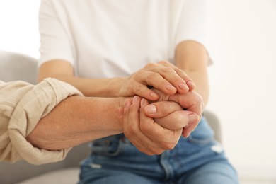 Photo of Caregiver supporting senior woman at home, closeup