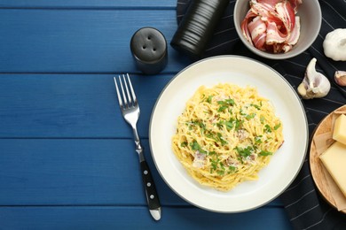 Photo of Delicious pasta Carbonara served on blue wooden table, flat lay