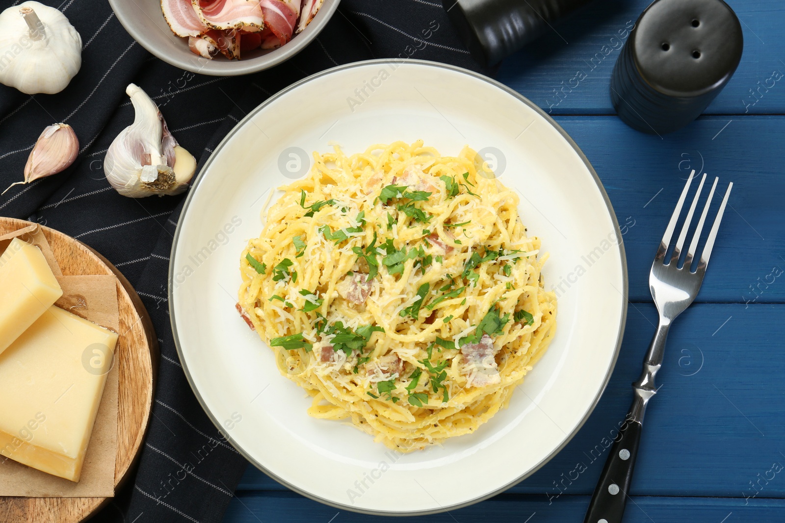 Photo of Delicious pasta Carbonara served on blue wooden table, flat lay