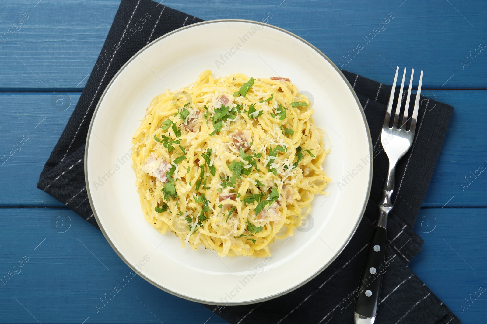 Photo of Delicious pasta Carbonara served on blue wooden table, flat lay