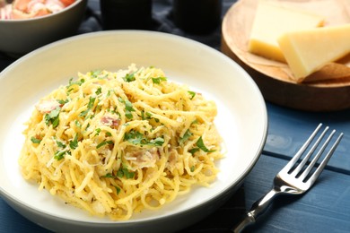 Photo of Delicious pasta Carbonara served on blue wooden table, closeup