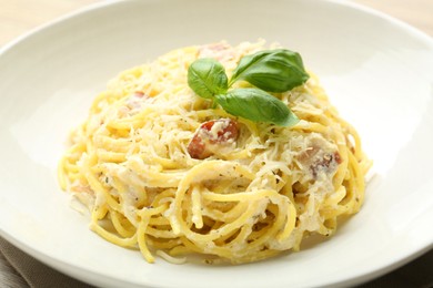 Photo of Delicious pasta Carbonara with basil in bowl, closeup