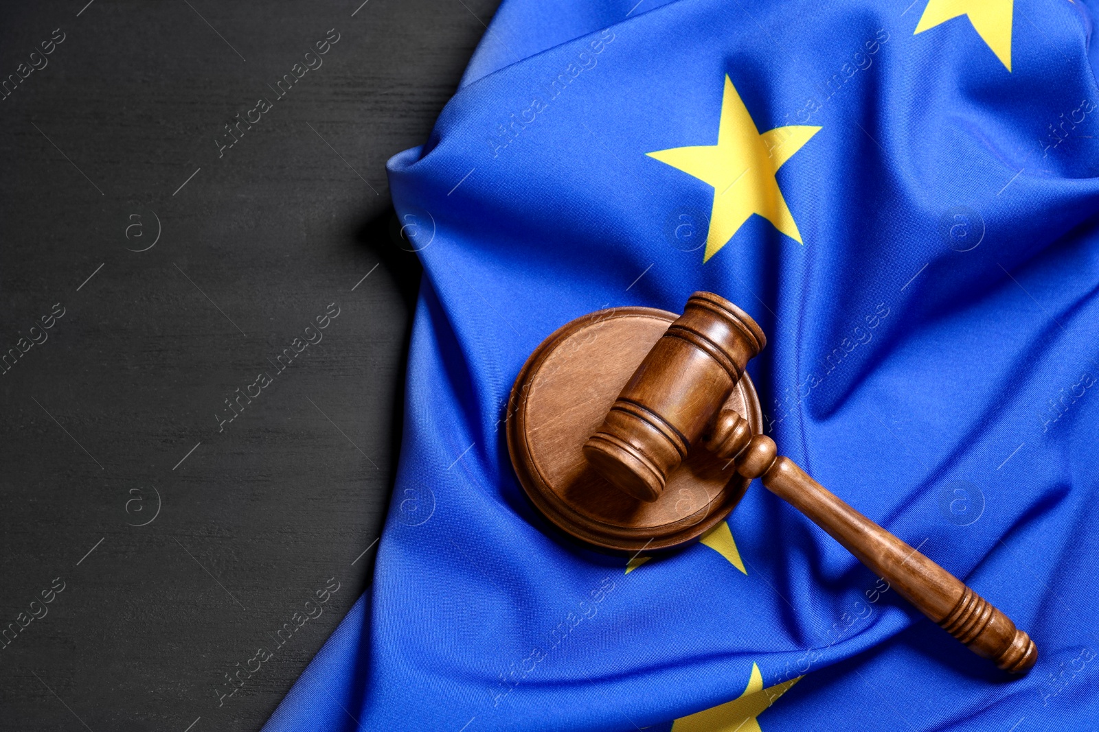 Photo of Judge's gavel and flag of European Union on grey wooden table, above view. Space for text