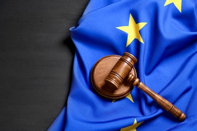 Photo of Judge's gavel and flag of European Union on grey wooden table, above view. Space for text