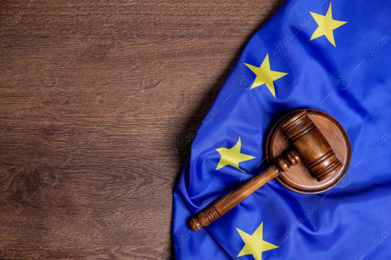 Photo of Judge's gavel and flag of European Union on wooden table, top view. Space for text