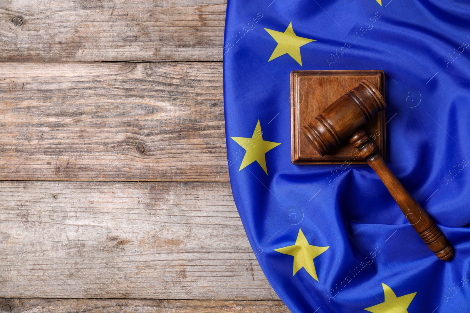 Photo of Judge's gavel and flag of European Union on wooden table, top view. Space for text