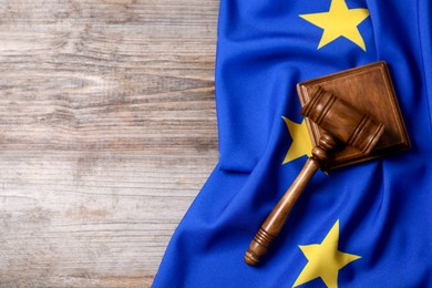 Photo of Judge's gavel and flag of European Union on wooden table, top view. Space for text