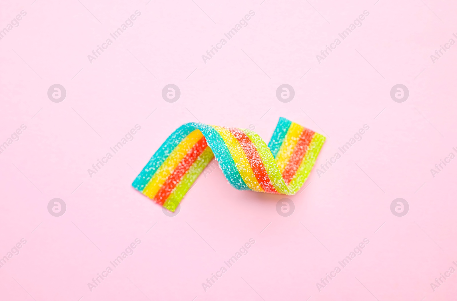 Photo of Tasty rainbow sour belt on pink background, top view