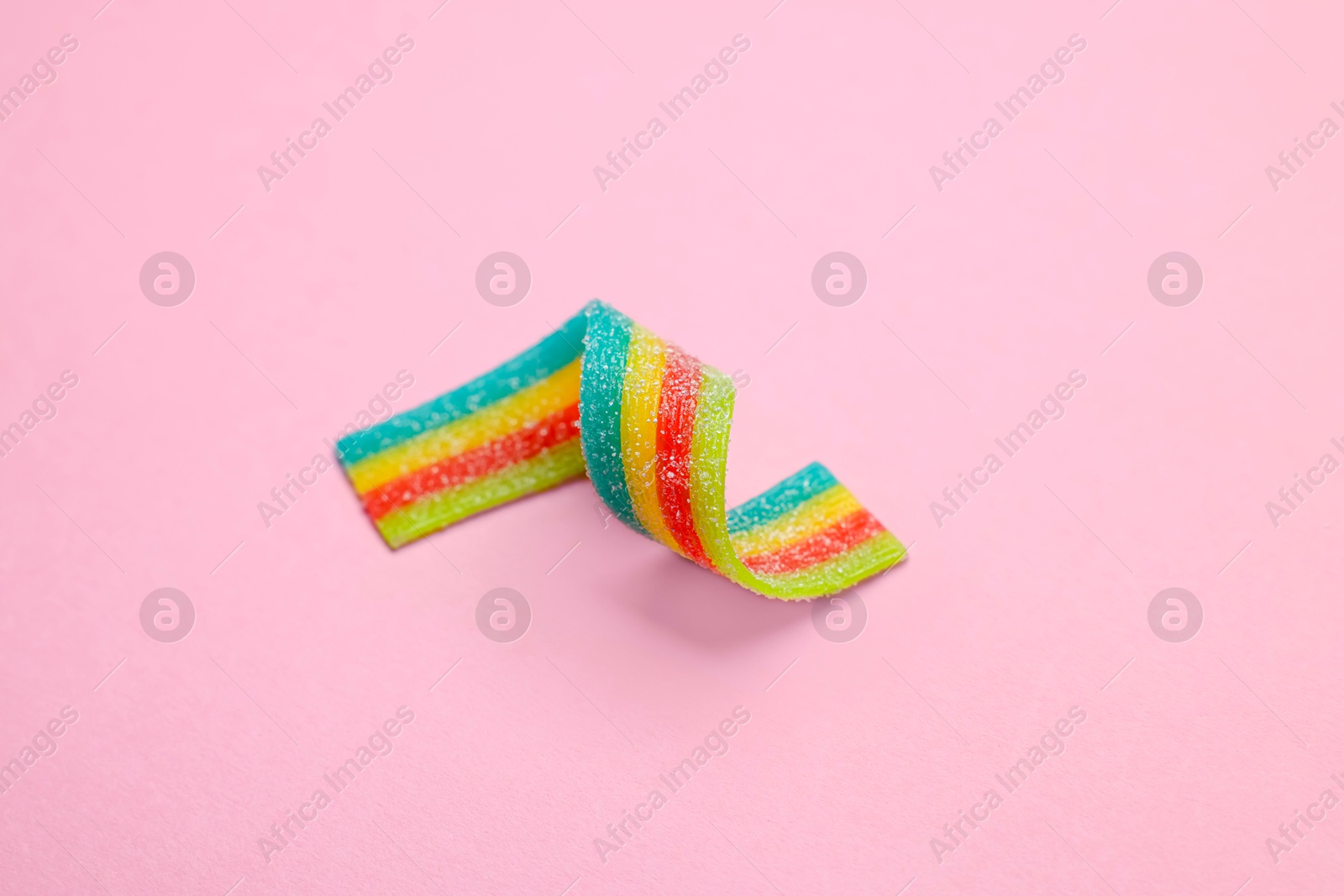 Photo of Tasty rainbow sour belt on pink background