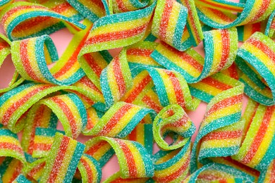 Photo of Tasty rainbow sour belts on pink background, top view