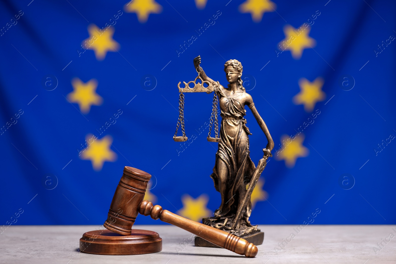 Photo of Figure of Lady Justice and judge's gavel on table against European Union flag