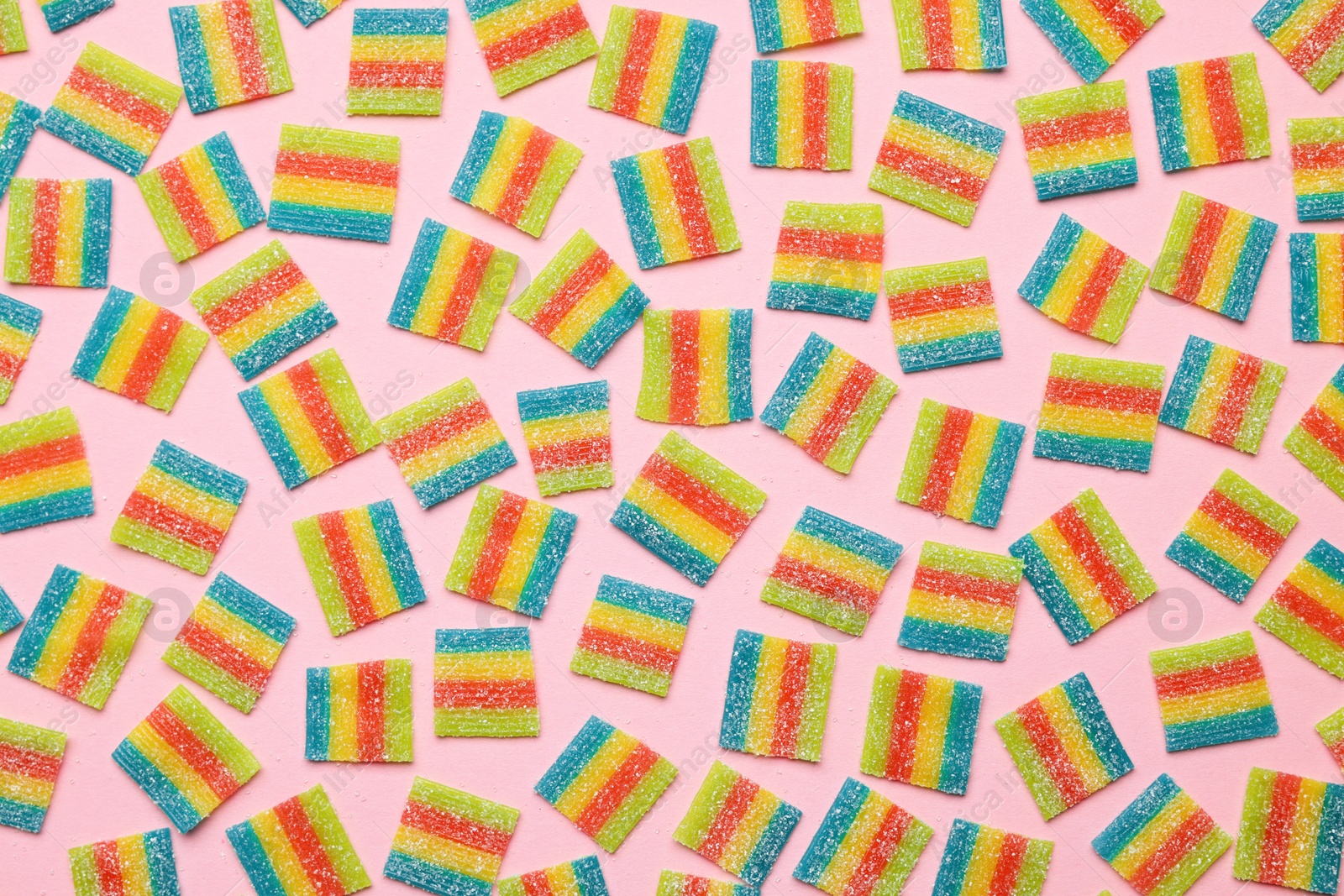 Photo of Tasty rainbow sour belts on pink background, top view