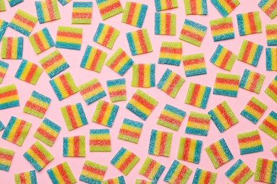 Photo of Tasty rainbow sour belts on pink background, top view