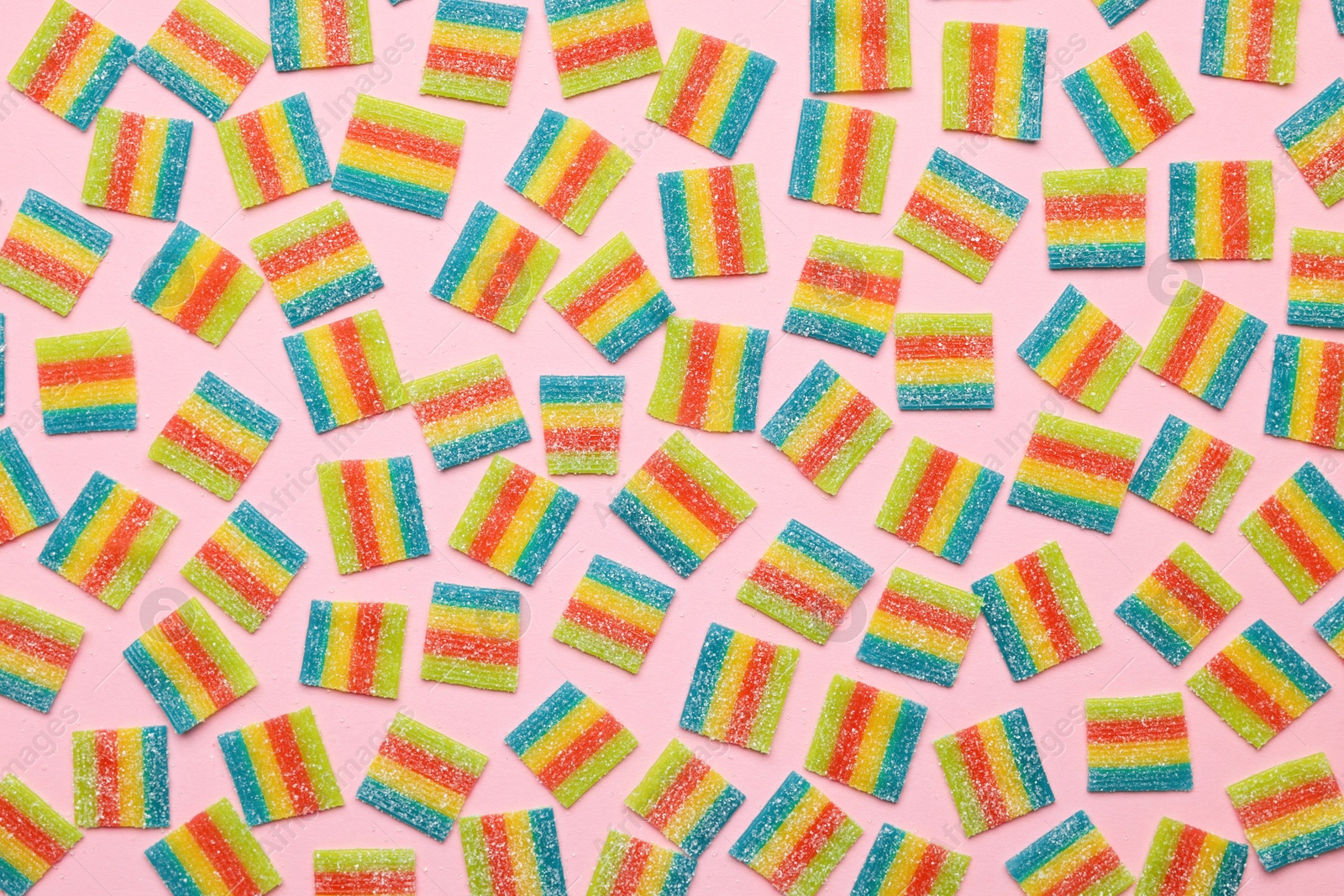 Photo of Tasty rainbow sour belts on pink background, top view